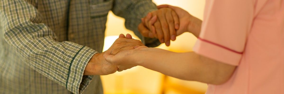 Senioren, die mit einer Pflegekraft Händchen halten